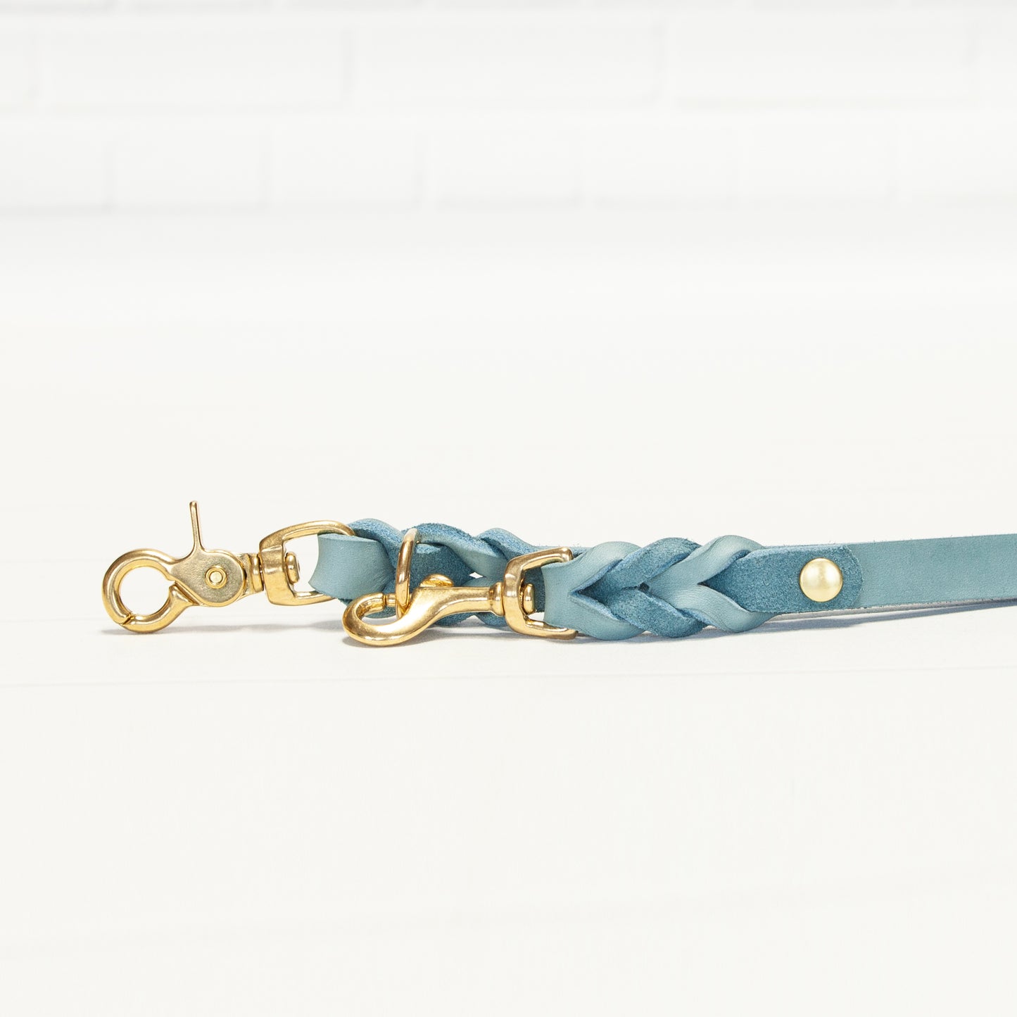 Die flach ausgebreitete MILA-Leine in Eisblau zeigt die präzise Flechtung und das harmonische Zusammenspiel mit den goldenen Metallteilen.