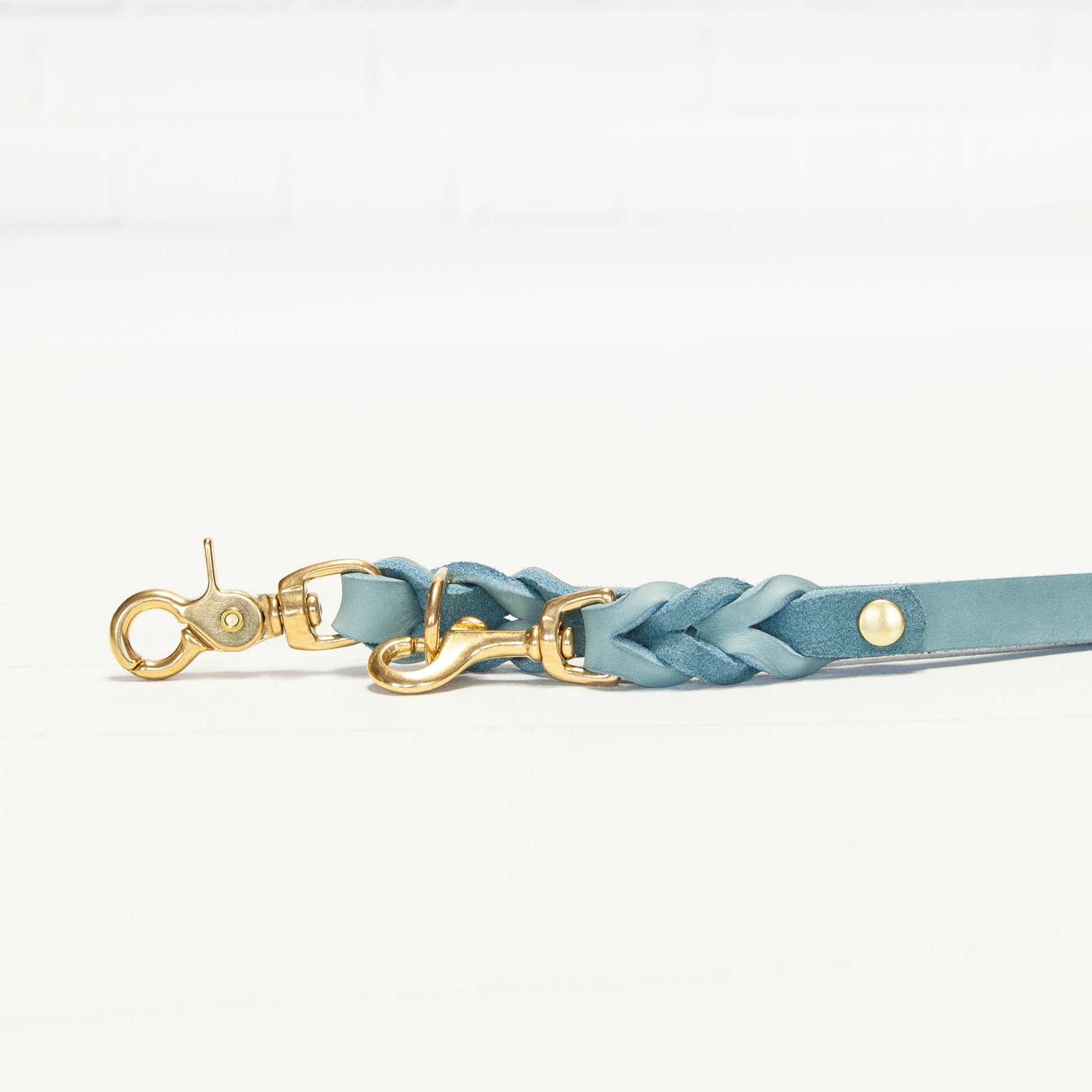 Die flach ausgebreitete MILA-Leine in Eisblau zeigt die präzise Flechtung und das harmonische Zusammenspiel mit den goldenen Metallteilen.